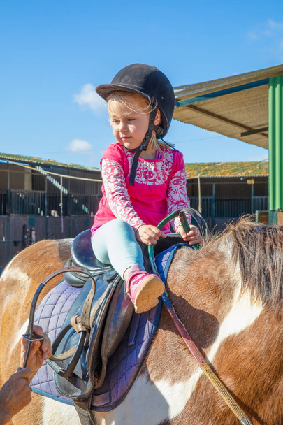 деталь милої маленької дівчинки готується їздити на коні поруч з
 - Фото, зображення