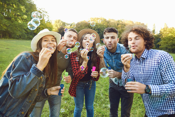 Young friends blowing soap bubbles in park - Zdjęcie, obraz