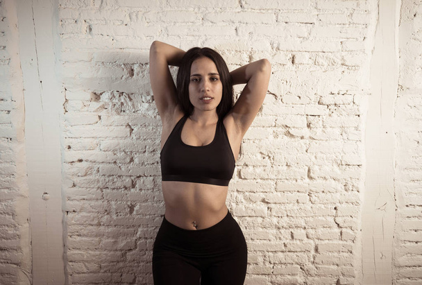 Beauty portrait of sport woman wearing gym suit looking sensual and fit. Studio shot of latin sexy strong woman in sportswear looking healthy posing against brick wall. In fitness Body care concept. - Fotó, kép