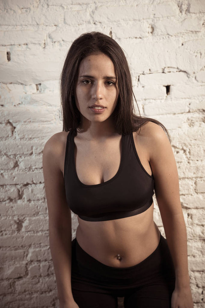 Beauty portrait of sport woman wearing gym suit looking sensual and fit. Studio shot of latin sexy strong woman in sportswear looking healthy posing against brick wall. In fitness Body care concept. - Foto, afbeelding