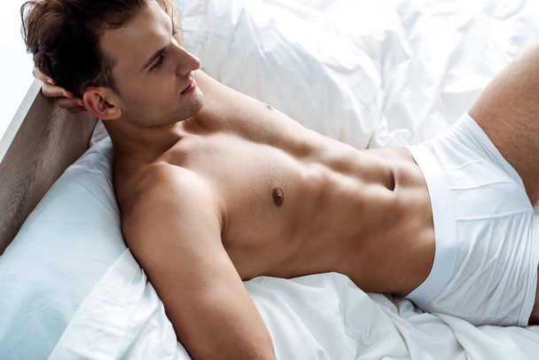 young handsome and sexy man lying on bed  - Fotografie, Obrázek