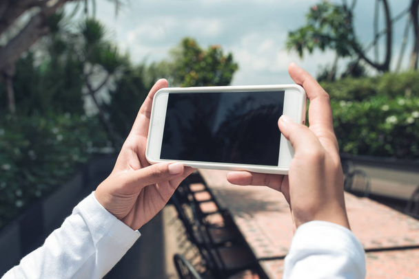 Mockup de mãos femininas segurando celular sem moldura com tela em branco e fazendo selfie em fundo isolado
. - Foto, Imagem