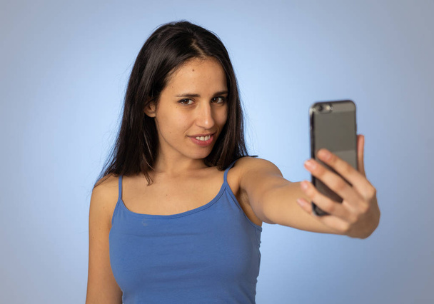 Studio shot of Young cool pretty latin teenager woman taking selfie with mobile smart phone having fun and looking beautiful sexy In millennial generation using mobile and social media addiction. - Foto, Imagem