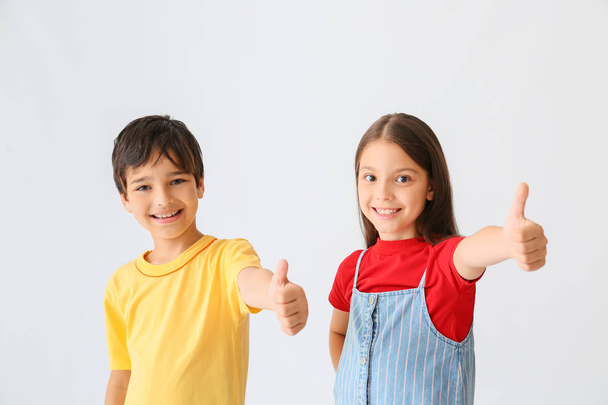 Retrato de niños felices mostrando gesto de pulgar hacia arriba sobre fondo claro
 - Foto, Imagen