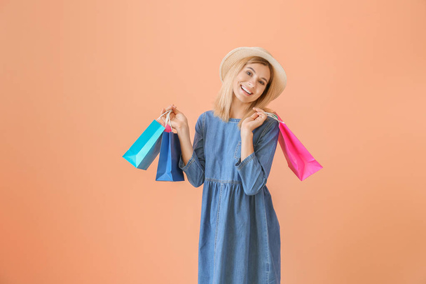 Happy beautiful woman with shopping bags on color background - Foto, Bild