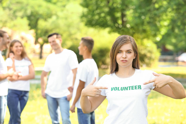 Kobieta wolontariusz wskazując na jej t-shirt na zewnątrz - Zdjęcie, obraz