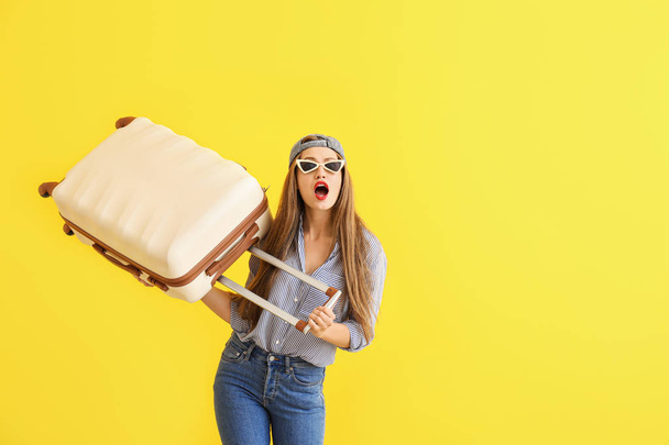 Wstrząśnięty młoda kobieta z walizką na kolorowym tle - Zdjęcie, obraz