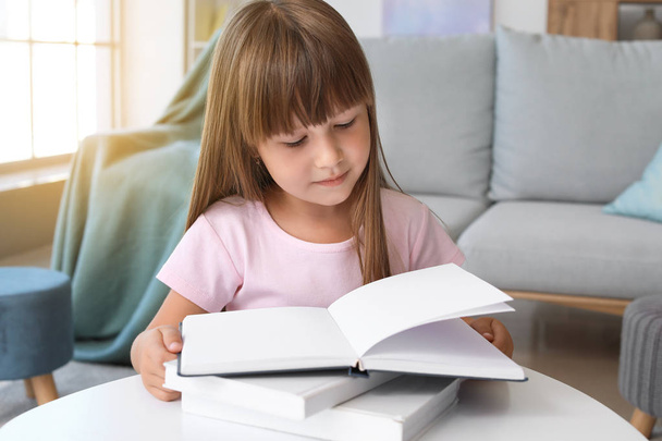 Cute little girl reading book at home - Fotó, kép