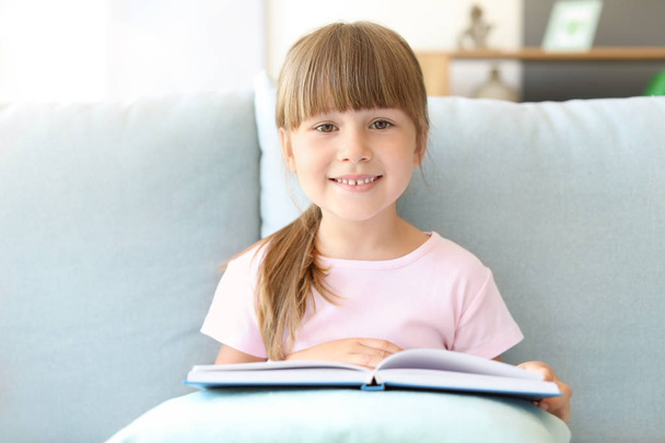 Söpö pieni tyttö lukeminen kirja kotona - Valokuva, kuva