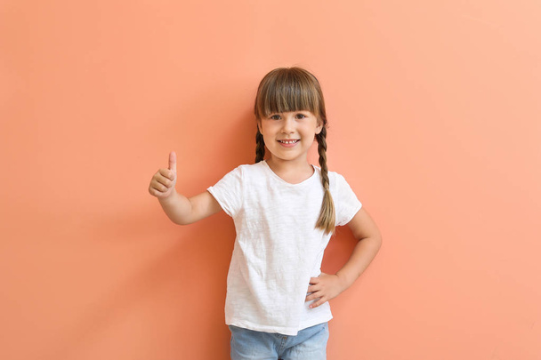 Little girl in stylish t-shirt showing thumb-up on color background - 写真・画像