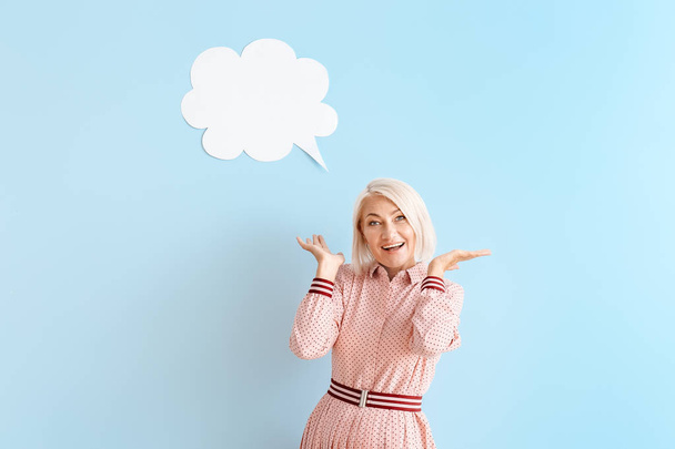 Mature woman with blank speech bubble on color background - Photo, Image