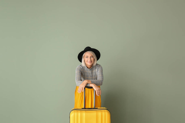 reife Frau mit Koffer auf farbigem Hintergrund - Foto, Bild