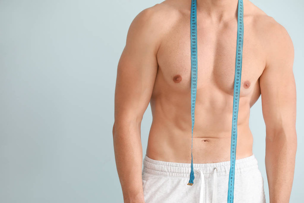 Handsome muscular man with measuring tape on color background. Weight loss concept - Foto, immagini