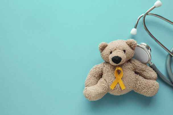 Children soft toy brown bear with yellow gold ribbon and stethos - Fotografie, Obrázek