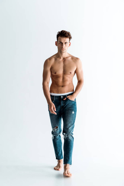 handsome man in jeans walking with hand in pocket on white  - Foto, immagini