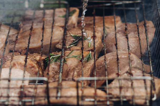 Grillowanie mięsa na grillu. Zbliżenie mięsa przygotowując się na sprzęt grilla na zewnątrz. Koncepcja grilla party. - Zdjęcie, obraz