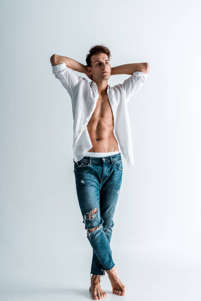 handsome young man in shirt and blue jeans standing on white  - Zdjęcie, obraz