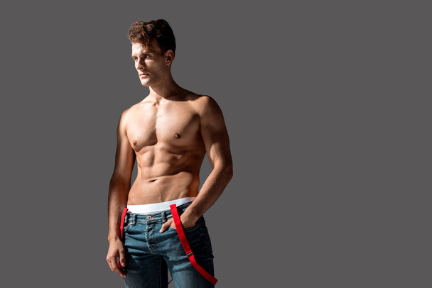 sexy man in blue jeans standing with hand in pocket isolated on grey   - Foto, Imagen