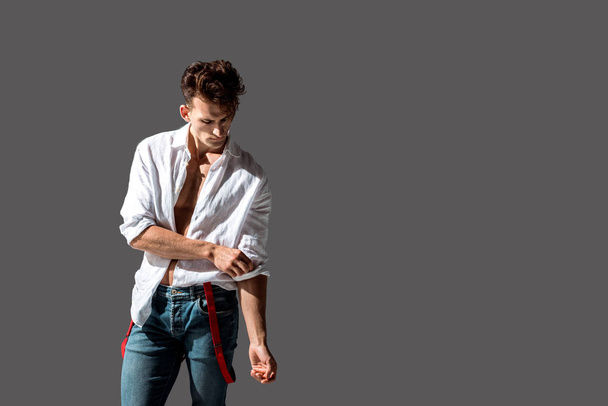 handsome man touching white shirt while standing isolated on grey  - Foto, immagini