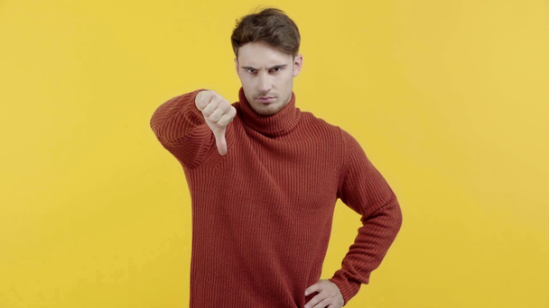chateado homem em suéter mostrando polegar para baixo isolado no amarelo
 - Filmagem, Vídeo