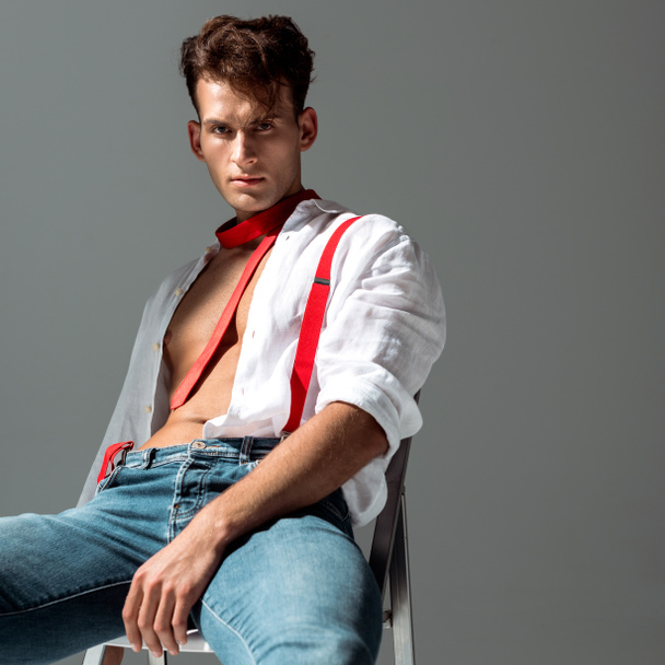 sexy man in white shirt sitting isolated on grey  - 写真・画像