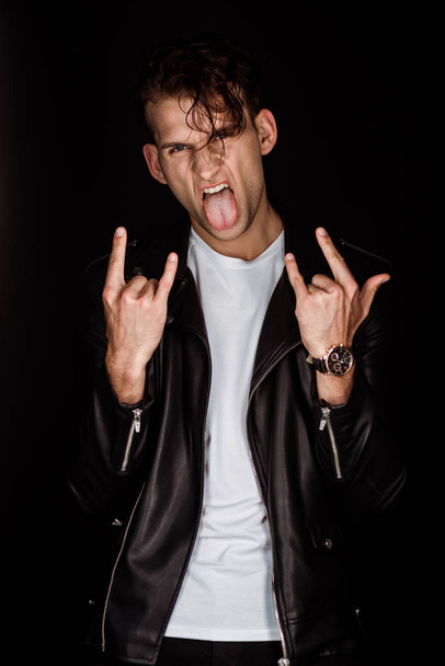 brutal man sticking out tongue and showing rock sign isolated on black  - Photo, Image