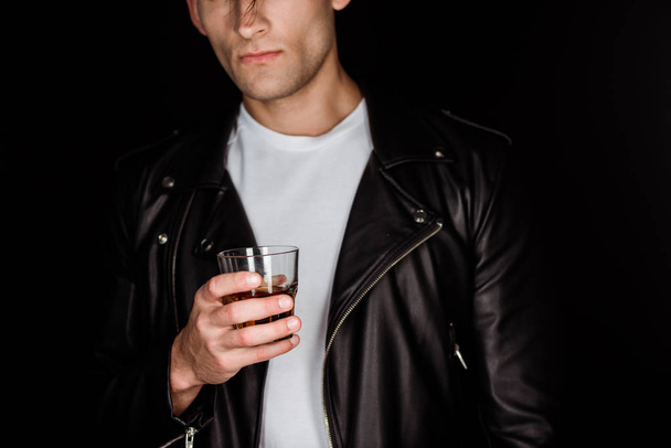 cropped view of trendy man holding glass with whiskey isolated on black  - Фото, изображение