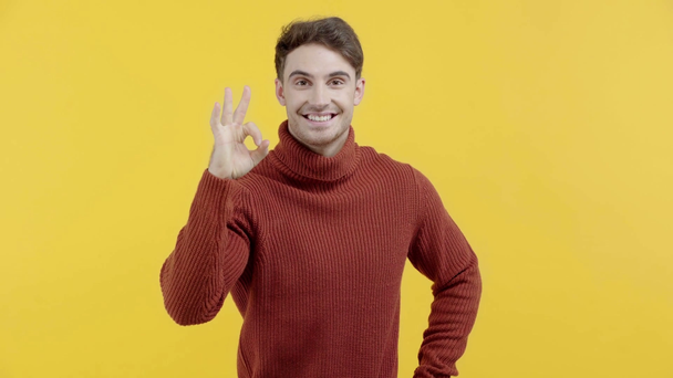 счастливый мужчина в свитере, показывающий знак "хорошо" на желтом
 - Кадры, видео