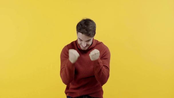 man in sweater praying and rejoicing isolated on yellow - Filmati, video