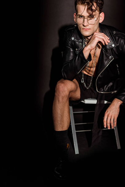 brutális és szexi férfi bőrkabát ül a fekete  - Fotó, kép