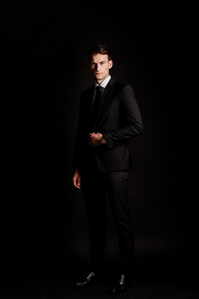 handsome businessman in suit standing isolated on black  - Fotografie, Obrázek