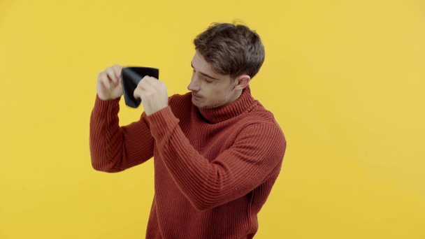 poor man in sweater shaking empty wallet isolated on yellow - Footage, Video