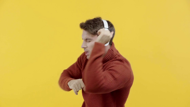 muž ve svetru a sluchátkách, izolovaný na žlutém - Záběry, video