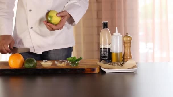 Kokki puhdistaa mangoa veitsellä. Pöydällä on appelsiini, avokado, salaatinlehdet.
. - Materiaali, video