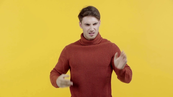 disgusted man in sweater smelling stench isolated on yellow - Footage, Video
