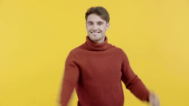 happy man in sweater showing yes gesture isolated on yellow - Materiał filmowy, wideo