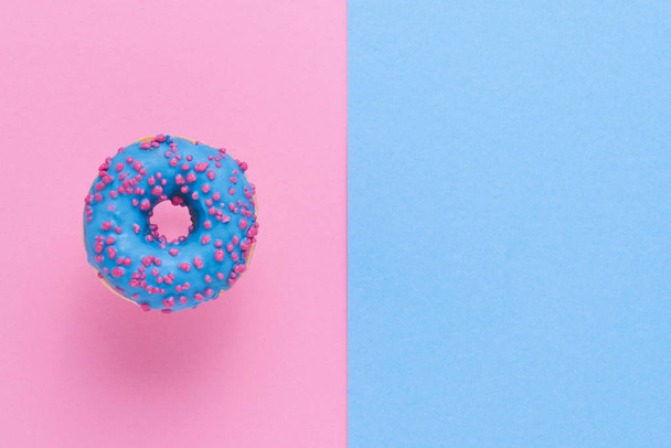 Sprinkled Blue Donut. Glazed sprinkled donut on pink blue background. Top view, copy space. - Photo, Image