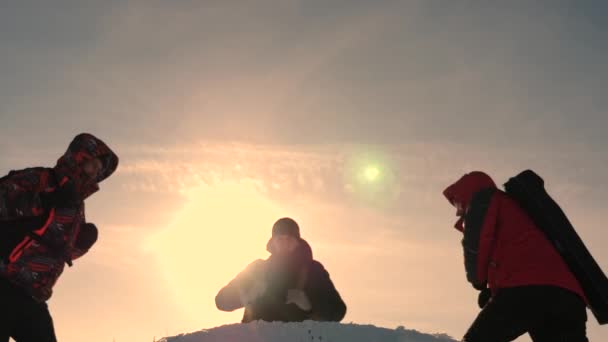 Alaskan travelers go to the top of a snowy hill and rejoice in victory against a winter sunset. team work of people. business teamwork, victory and success. Tourists met on top of success. - Footage, Video