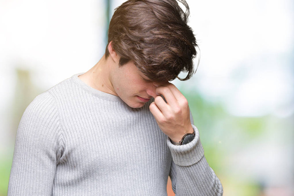 Jonge knappe man winter trui dragen over geïsoleerde achtergrond moe wrijven neus en ogen, vermoeidheid en hoofdpijn gevoel. Stress en frustratie concept. - Foto, afbeelding