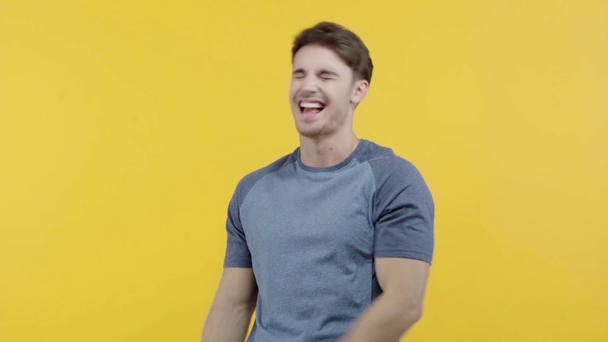 happy young man laughing isolated on yellow - Materiał filmowy, wideo