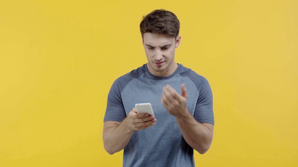 黄色で隔離されたスマートフォンでショックを受けた男のテキストメッセージ - 映像、動画