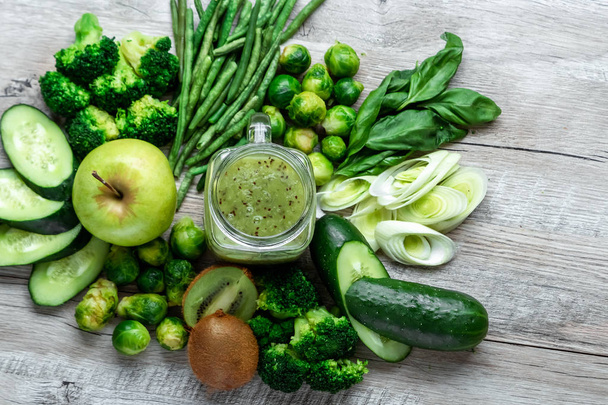 Fresh green food on a light table. Avocados cucumbers cabbage apples beans kiwi onions broccoli. The concept of healthy food, detox vegetarianism. Copy space flat lay. - Fotó, kép