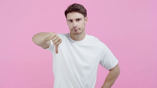 szomorú ember mutatja hüvelykujját le elszigetelt a rózsaszín - Felvétel, videó