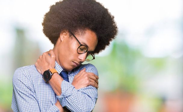 Young african american business man with afro hair wearing glasses Hugging oneself happy and positive, smiling confident. Self love and self care - Photo, Image