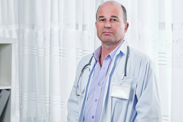 Boş rozeti kameraya bakarak beyaz labcoat üzgün ciddi doktor portresi - Fotoğraf, Görsel