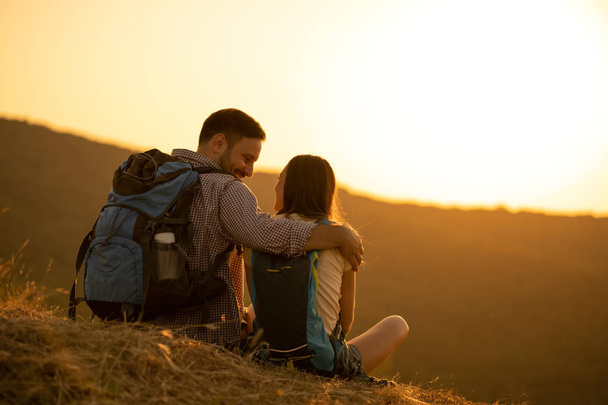 Mladý šťastný pár je turistika v horách a při pohledu na západ slunce. - Fotografie, Obrázek