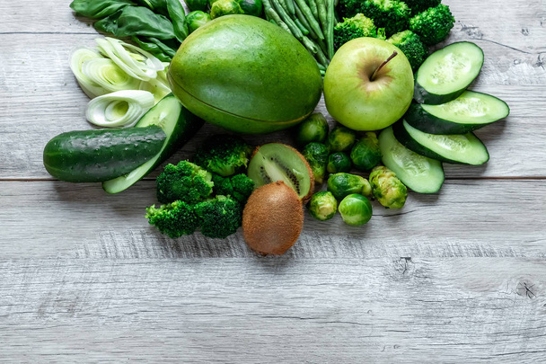 Fresh green food on a light table. Avocados cucumbers cabbage apples beans kiwi onions broccoli. The concept of healthy food, detox vegetarianism. Copy space flat lay. - Foto, immagini