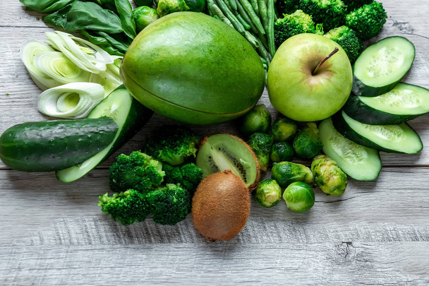 Fresh green food on a light table. Avocados cucumbers cabbage apples beans kiwi onions broccoli. The concept of healthy food, detox vegetarianism. Copy space flat lay. - Fotoğraf, Görsel