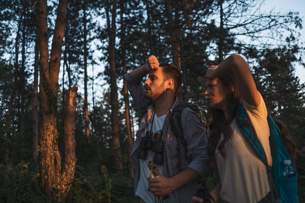 若いカップルが森の中をハイキングしている。疲れている. - 写真・画像