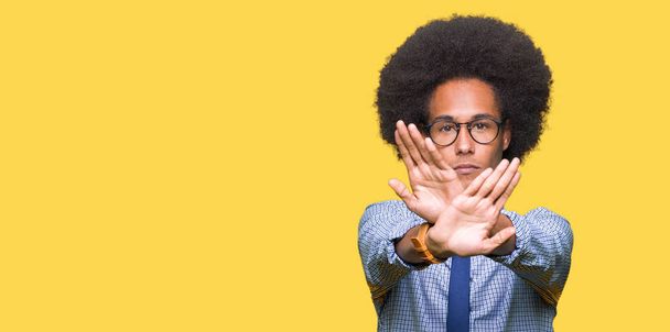 Joven hombre de negocios afroamericano con cabello afro usando gafas Expresión de rechazo cruzando brazos y palmas haciendo signo negativo, cara enojada
 - Foto, Imagen